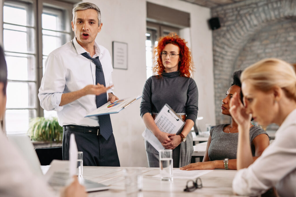 Angry businessman feeling disappointed with business reports and scolding his team during a meeting in the office. sales team problems